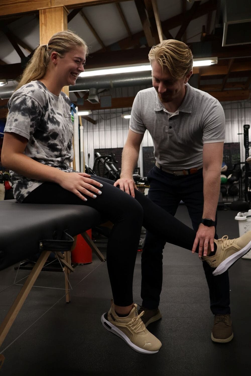 AIMPT - A physical therapist examines a young woman’s leg as she sits on an exam table in a clinic. - Charleston, South Carolina